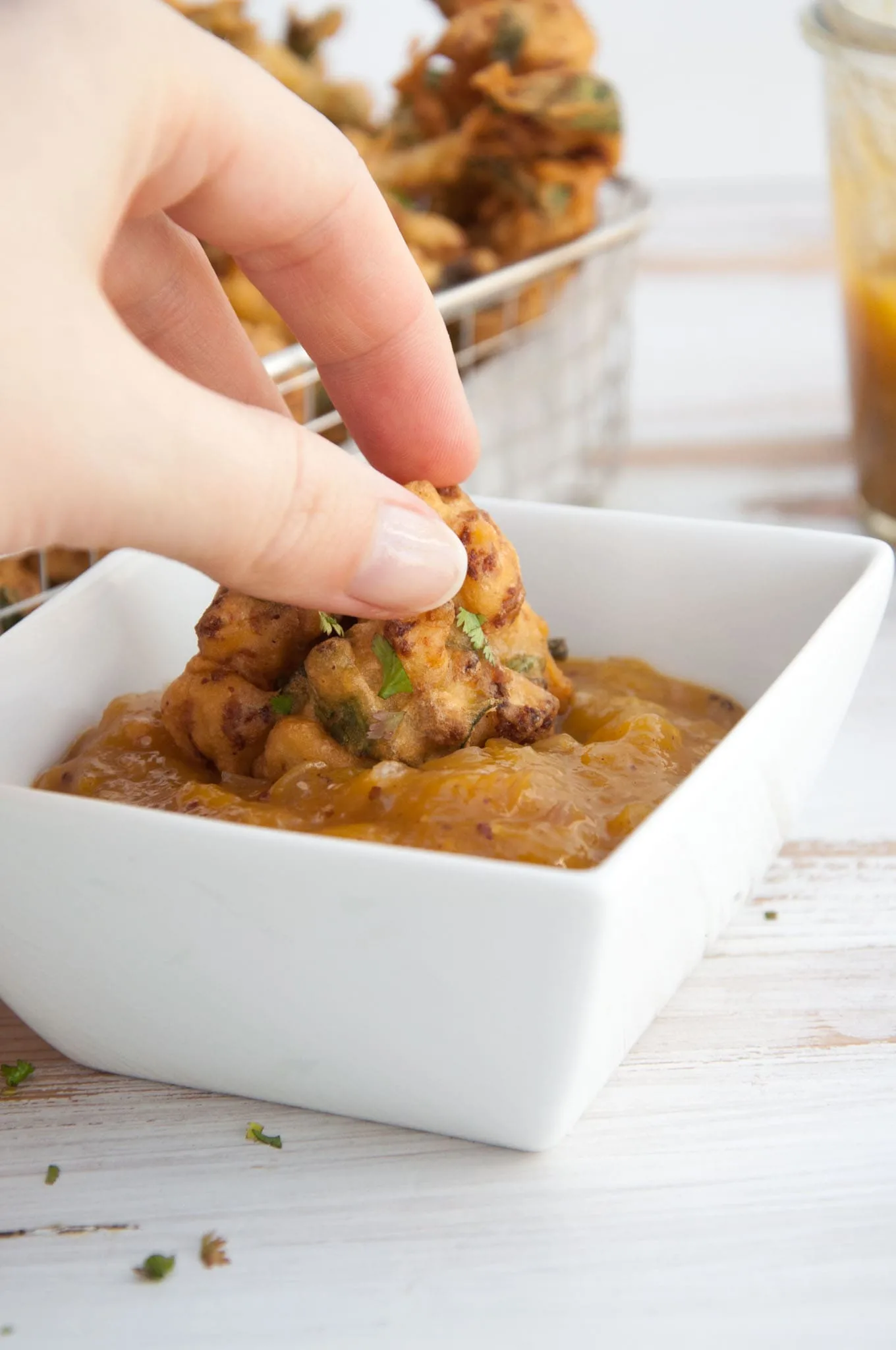 Vegetable Pakora being dipped in Mango Chutney