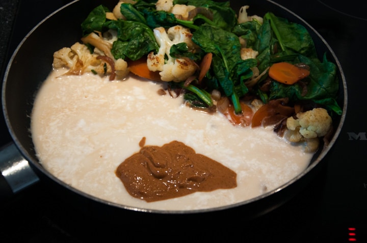 adding coconut milk and peanut butter to veggies