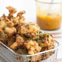 Vegetable Pakoras in a basket with mango chutney in the background