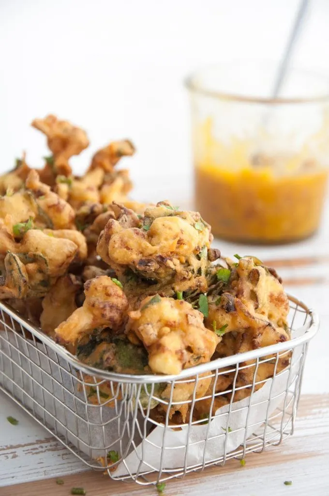 Vegetable Pakoras in a basket with mango chutney in the background