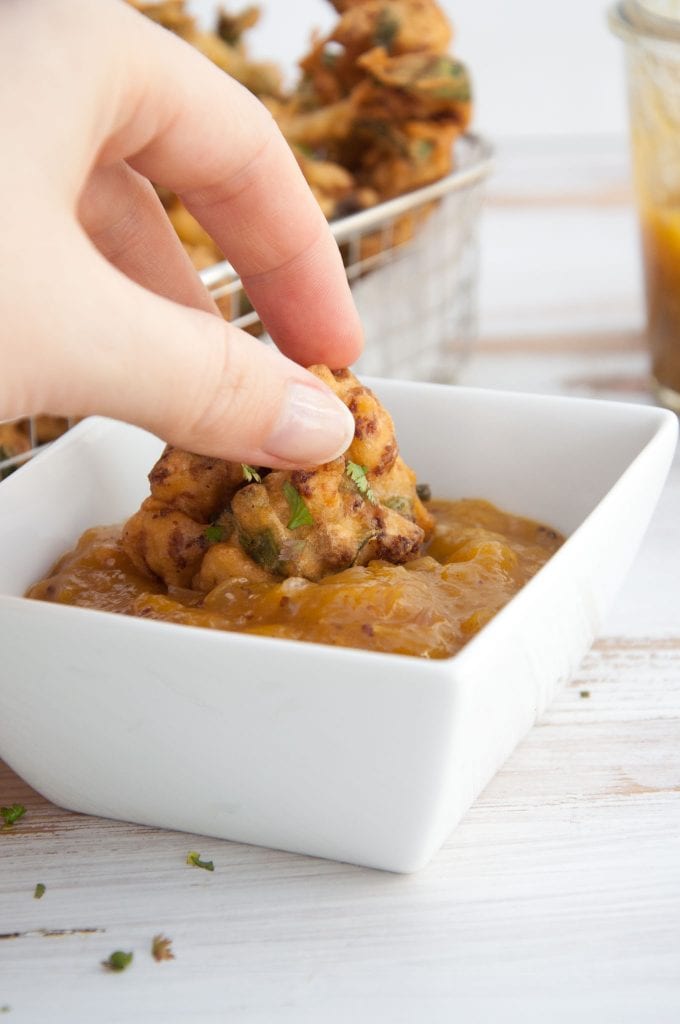 Vegetable Pakoras being dipped in Mango Chutney