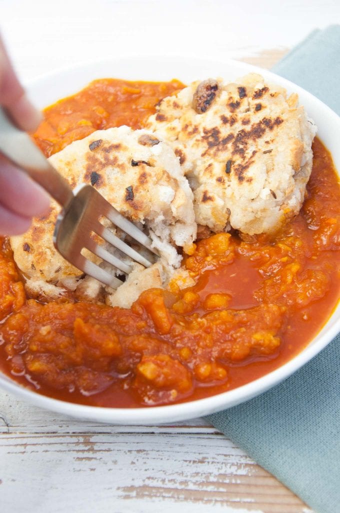 A fork digging into Vegan Pumpkin Goulash with two pan-fried Bread Dumplings