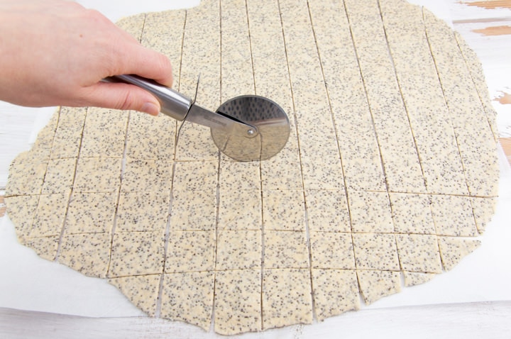 using a pizza cutter to cut the dough into crackers