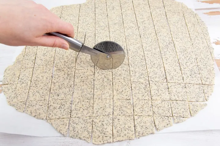 using a pizza cutter to cut the dough into crackers