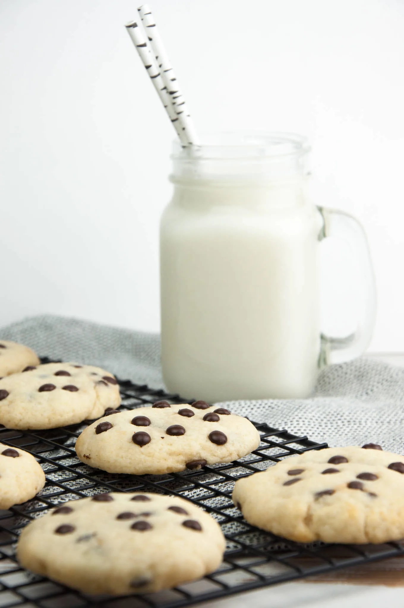 Soft Baked Vegan Chocolate Chip Cookies with plant-based milk in the background
