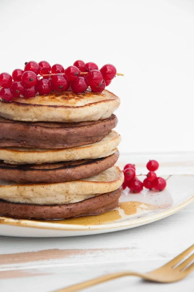 Vegan Cocoa and Vanilla Pancake Tower from the side, topped with red currant
