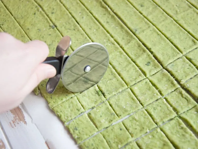 Cutting spinach crackers with a pizza cuter