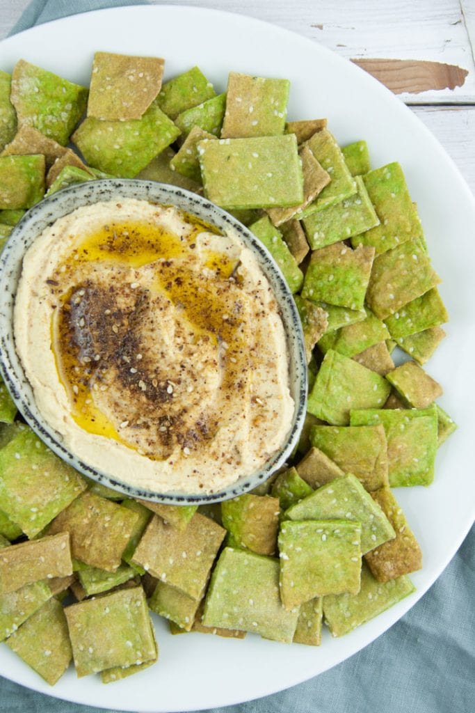 Cracker di sesamo di spinaci vegani serviti con Hummus Zaatar