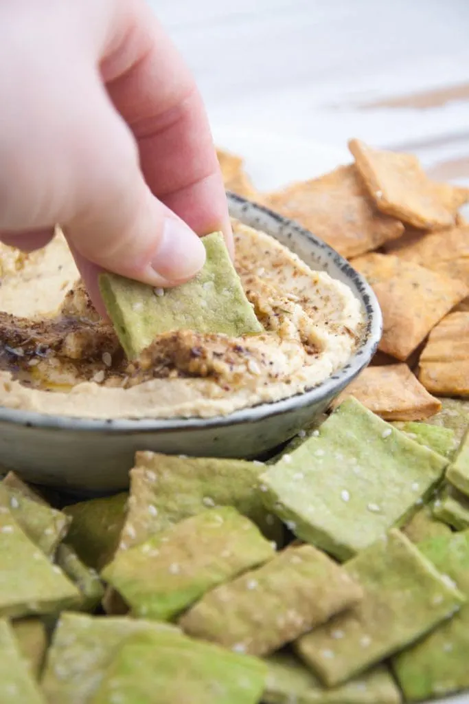 Vegan Spinach Sesame Crackers dipped into Zaatar Hummus