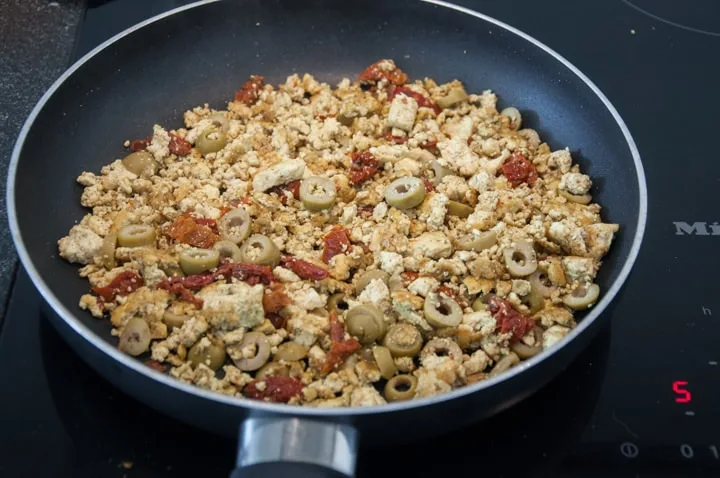 tofu scramble with olives and dried tomatoes in pan