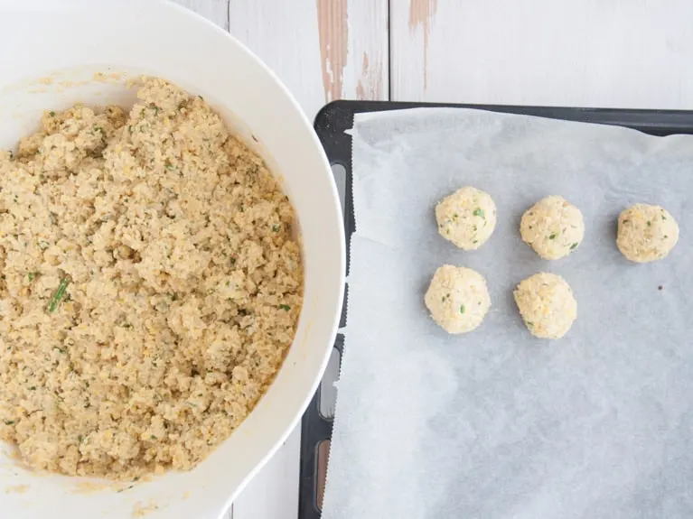 Falafel mixture and a few falafels on a baking tray