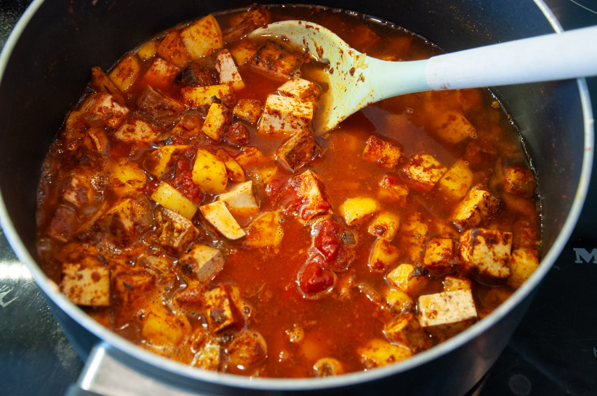 adding water and tomato paste to the goulash