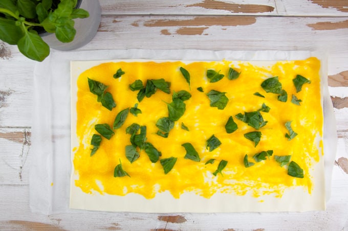 Puff Pastry dough spread with pumpkin purée and fresh basil