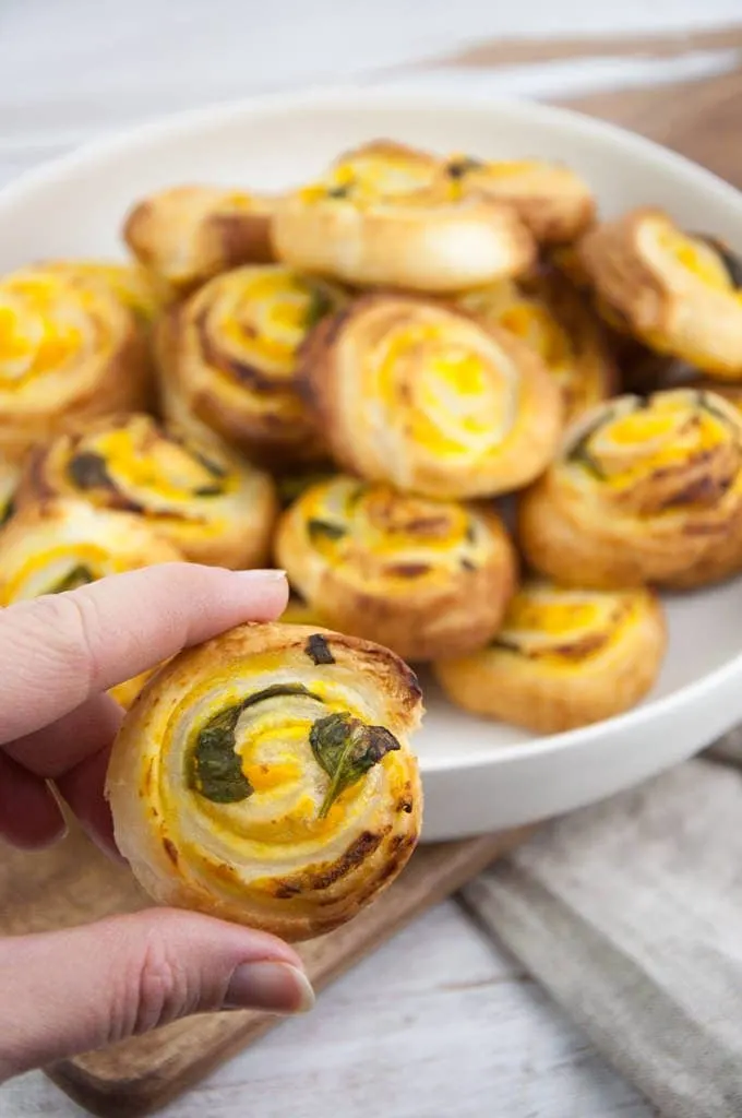holding a pumpkin basil pinwheel between two fingers