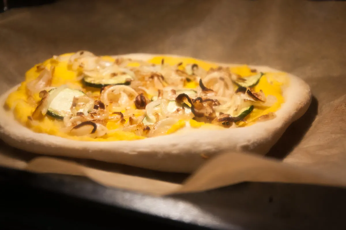 Vegan Pumpkin Pizza with caramelized onions and zucchini in the oven