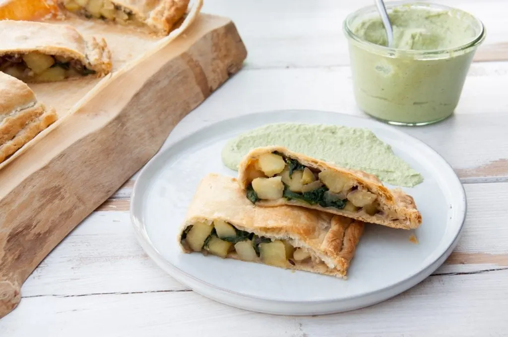 Vegan Potato and Spinach Strudel from the side with cilantro sunflower sauce in the background