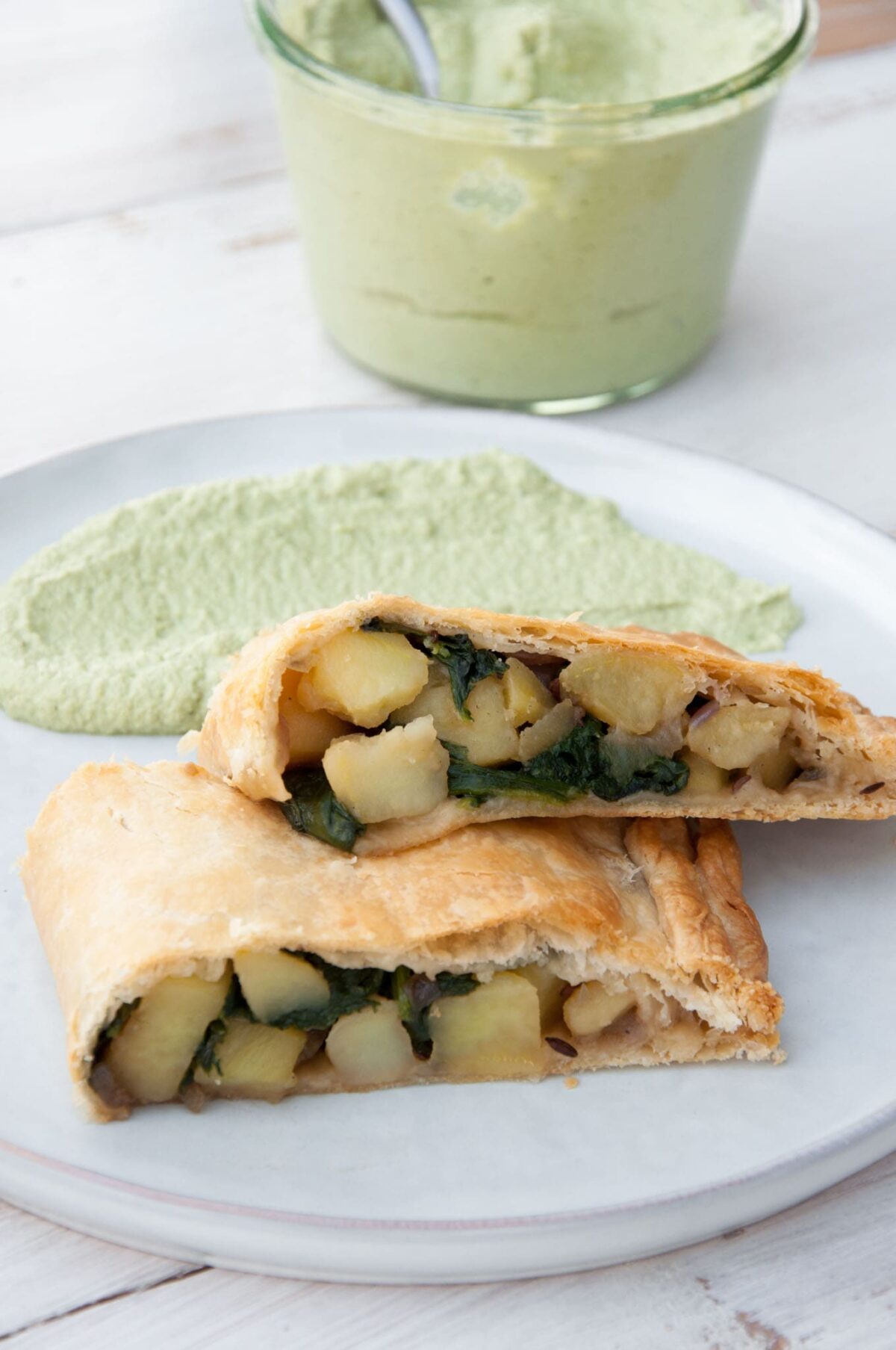 Vegan Potato and Spinach Strudel from the side with cilantro sunflower sauce in the background