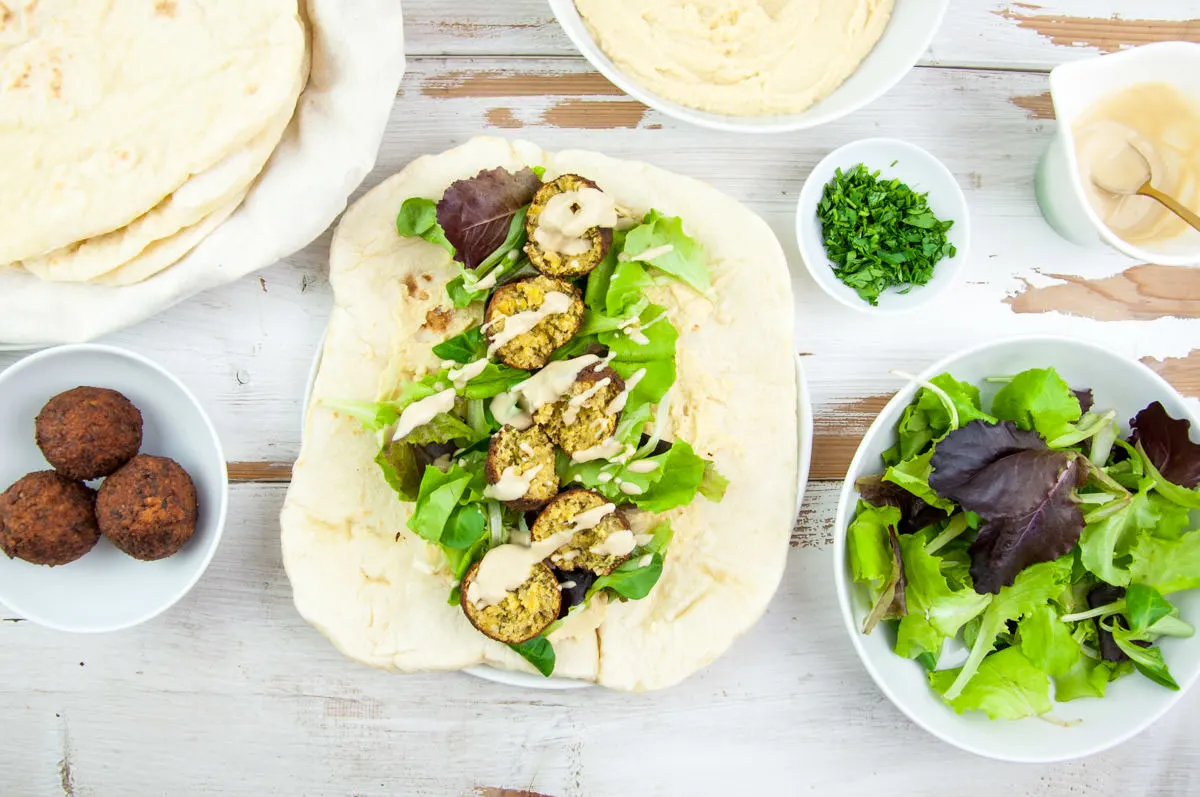 Vegan Falafel Wrap with homemade falafel, tortillas, lettuce, hummus, tahini sauce and fresh parsley