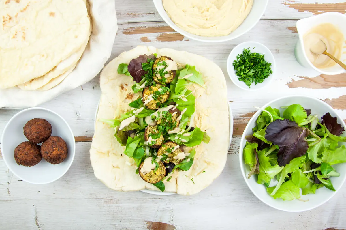 Vegan Falafel Wrap with homemade falafel, tortillas, lettuce, hummus, tahini sauce and fresh parsley