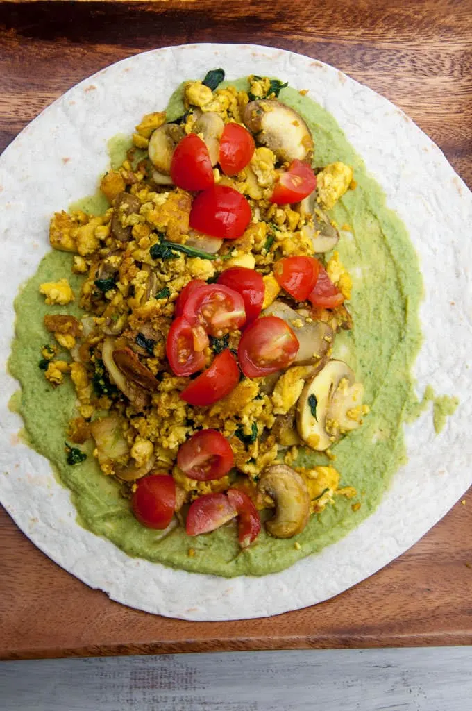 open-faced Mushroom Spinach Tofu Wrap consisting of tofu scramble, cilantro hummus, mushrooms, spinach and tomatoes