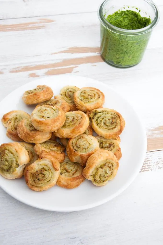 Vegan Arugula Pesto Pinwheels on a plate with pesto in the background