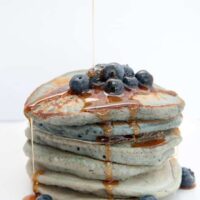Stack of Blue Pancakes drizzled with maple syrup