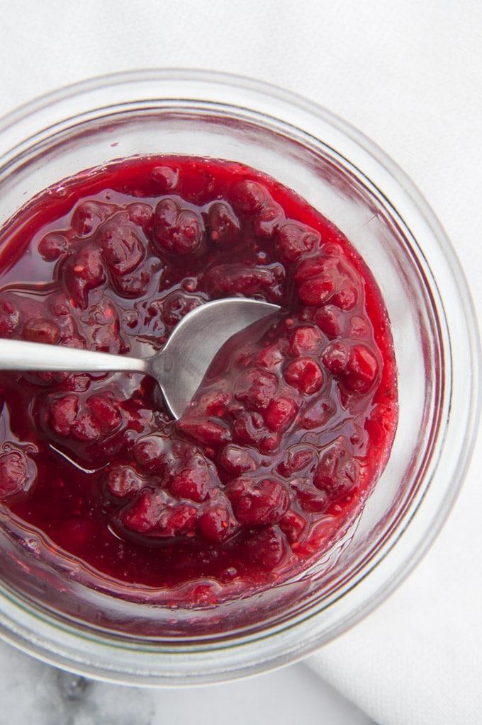 Vegan Lingonberry Jam in a glass jar with a spoon