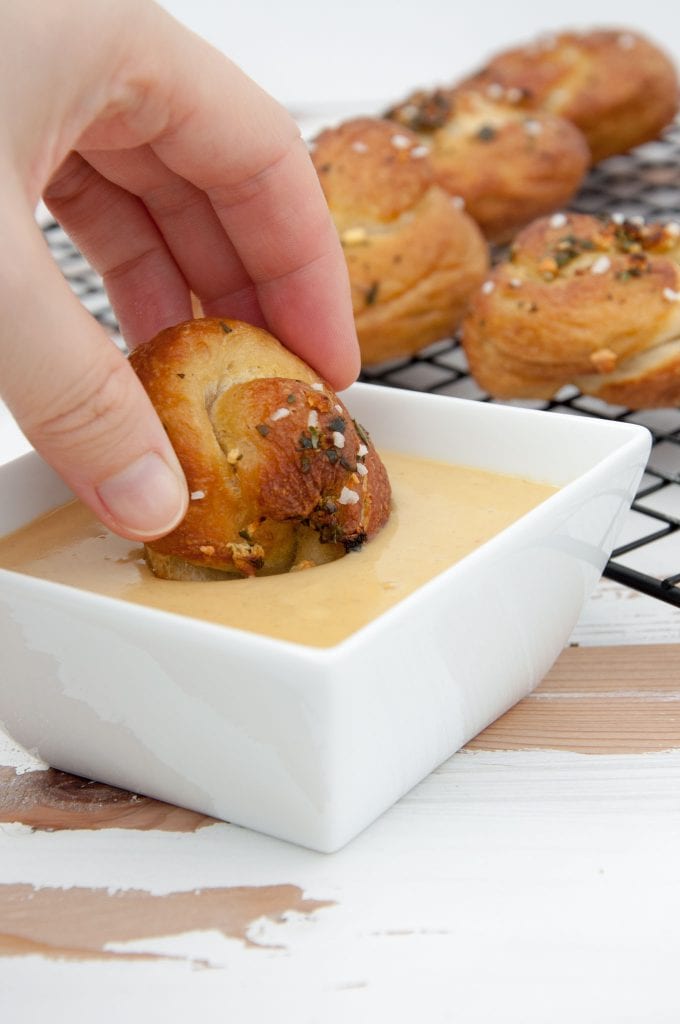 A Pretzel Garlic Knot being dipped in vegan cheese