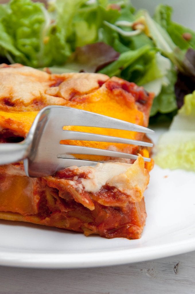 Eine Gabel die in ein Stück Kürbis-Lasagne mit Cashew-Käse sticht