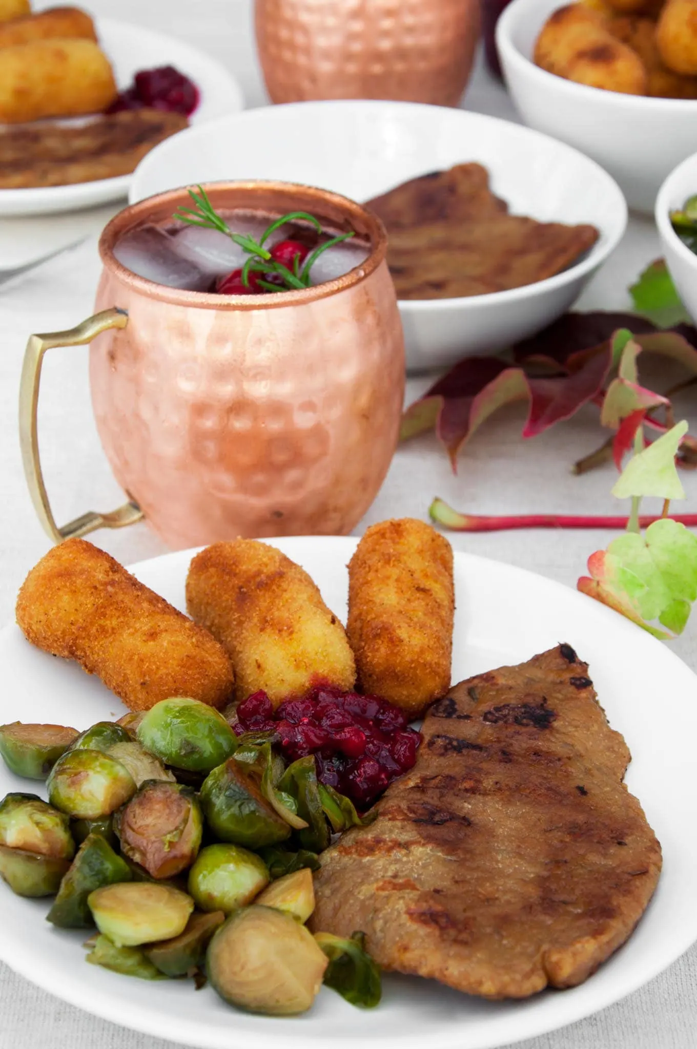 Vegan Thanksgiving Plate with seitan steaks, brussels sprouts, potato croquettes, lingonberry jam and cranberry moscow mule