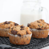 Chunky Monkey Muffins on a cooling rack with milk in the background