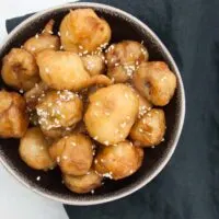 Vegan Banana Fritters coated in maple syrup and sprinkled with sesame seeds