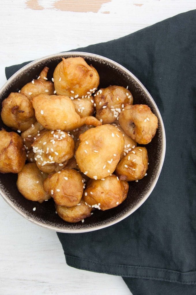 Vegan Banana Fritters coated in maple syrup and sprinkled with sesame seeds