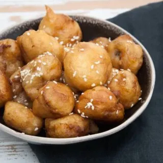 Vegan Banana Fritters coated in maple syrup and sprinkled with sesame seeds