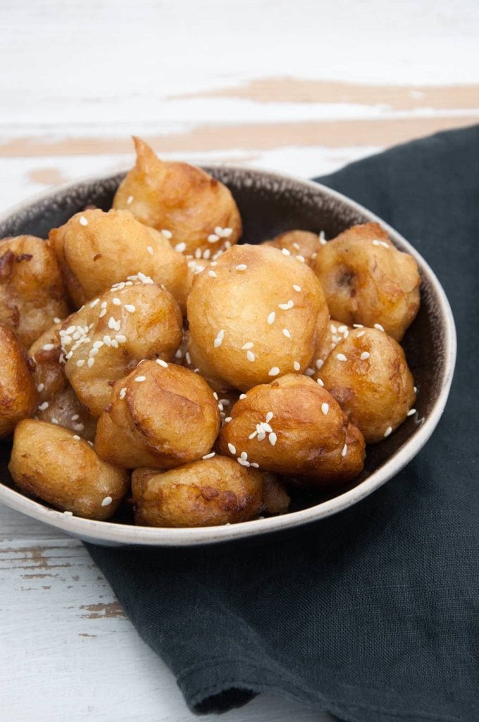 Vegan Banana Fritters coated in maple syrup and sprinkled with sesame seeds