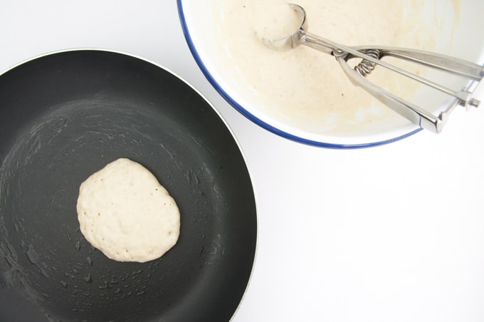 Adding pancake batter into a pan with a ice cream scoop