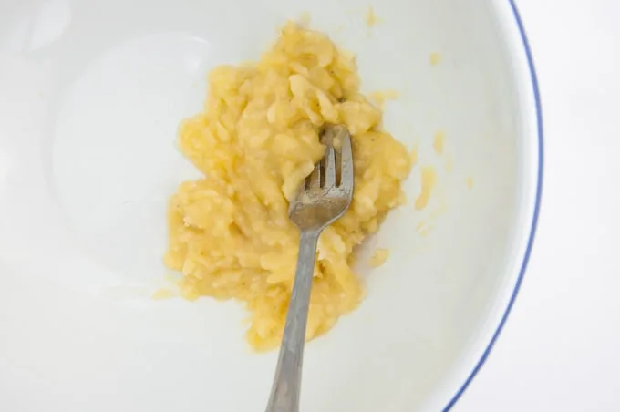 Mashed banana in a bowl with a fork