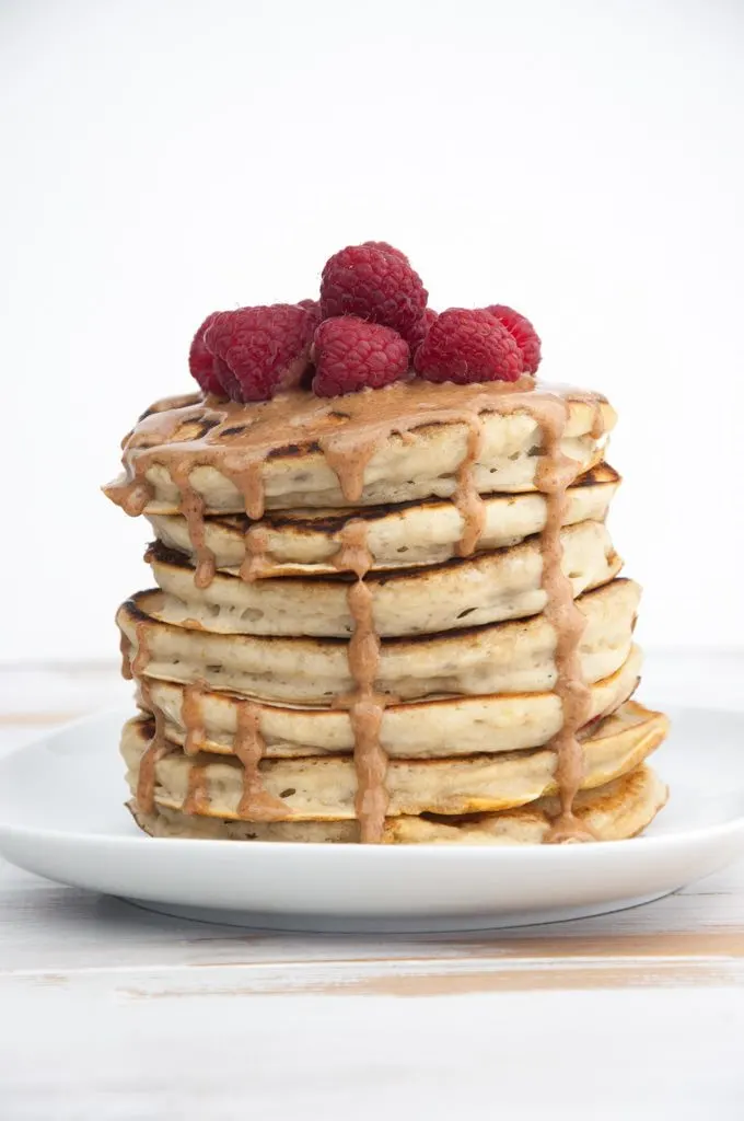 Fluffy Vegan Banana Pancakes topped with almond butter and raspberries