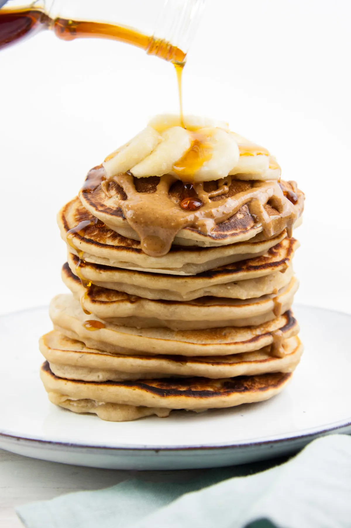 Vegan Protein Pancakes topped with peanut butter, banana slices and maple syrup