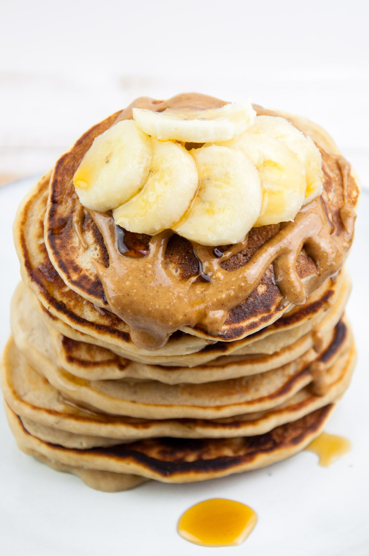 Vegan Protein Pancakes topped with peanut butter, banana slices and maple syrup