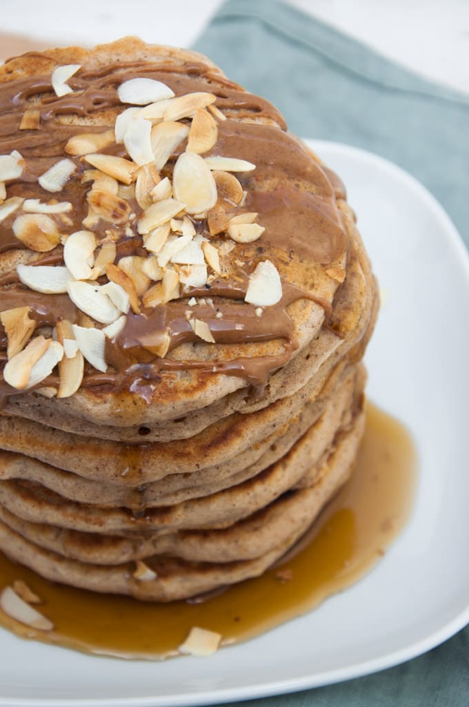 Vegan Apple Pie Pancakes topped with maple syrup, almond butter and toasted almonds