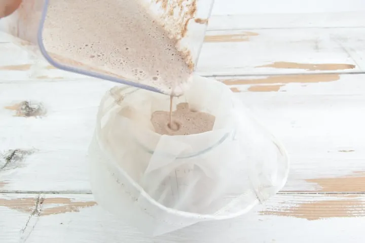 pouring chocolate hazelnut milk through a nut bag