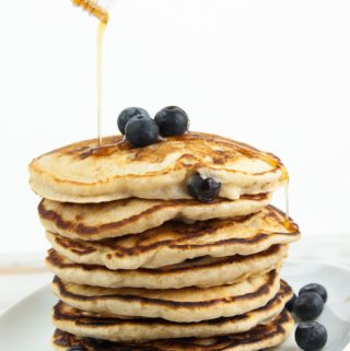 a stack of fluffy vegan blueberry pancakes drizzled with maple syrup