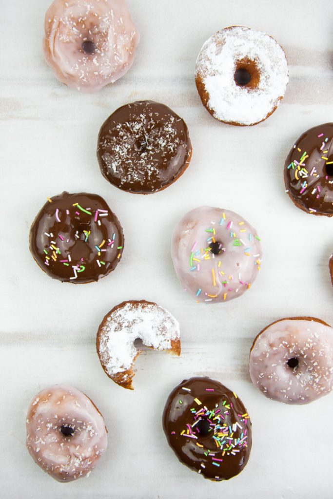 various vegan donuts with chocolate, pink glaze, powdered sugar, and sprinkles
