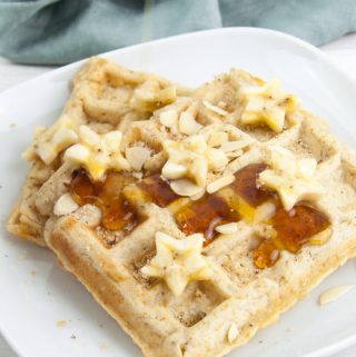 Vegan Banana Bread Waffles topped with maple syrup, banana slices, toasted almond slices and hazelnut meal