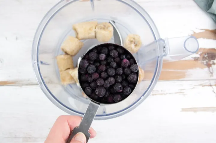 frozen bananas and frozen blueberries going into a food processor