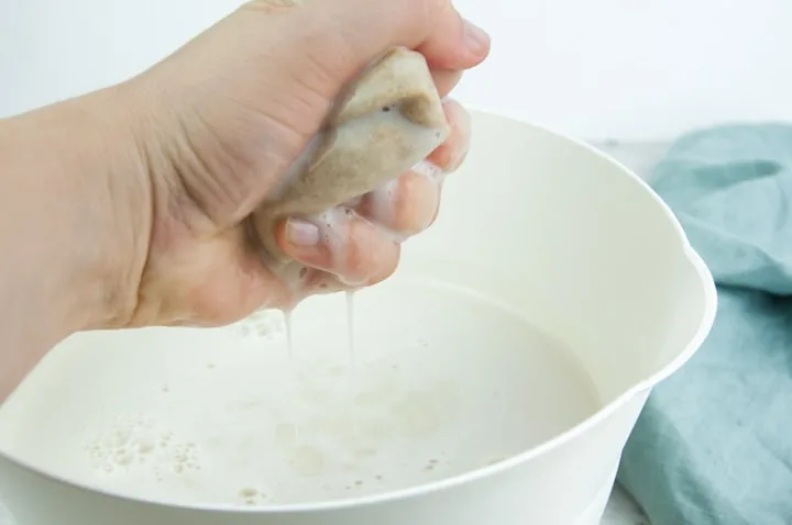 squeezing excess milk out of the nut milk bag