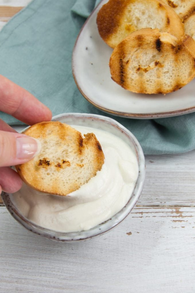 dipping toasted bread in vegan aioli