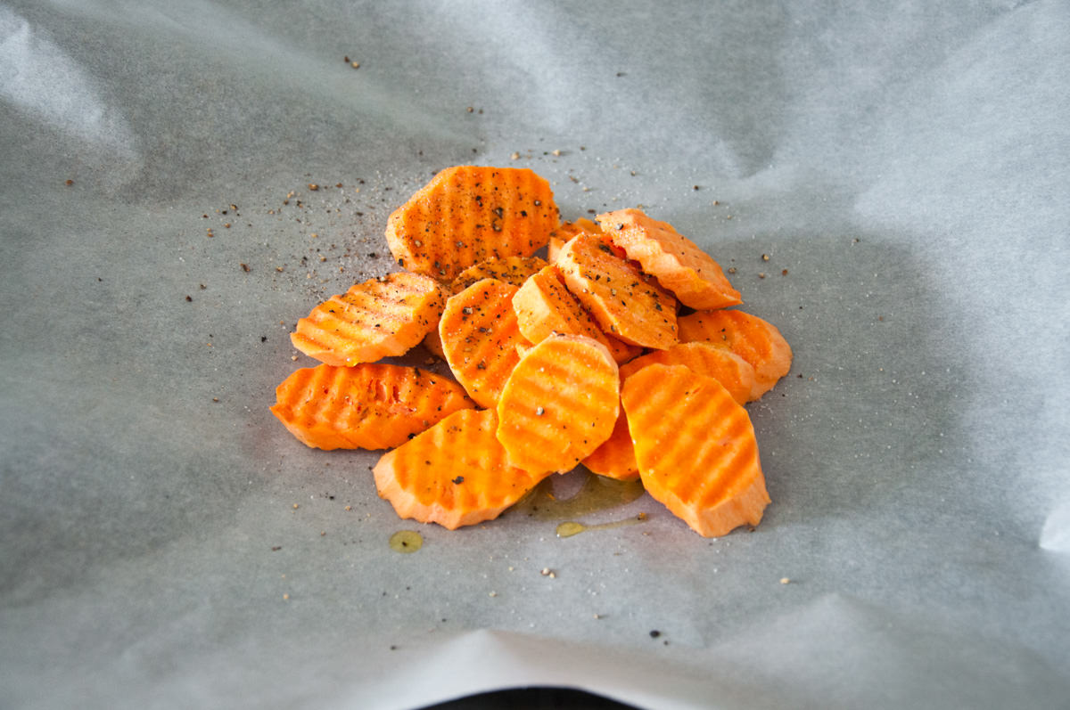 sweet potato slices, olive oil, salt and pepper on parchment paper