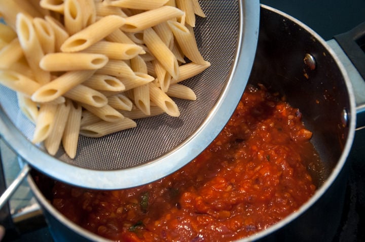 adding pasta to carrot bolognese sauce